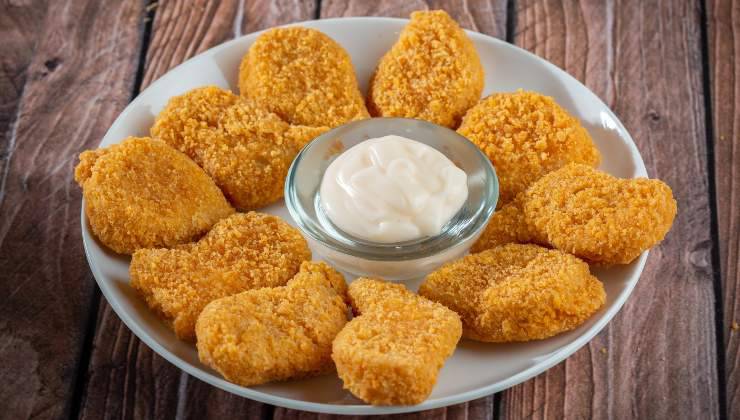 Nuggets di pollo nel piatto che il gatto vorrebbe