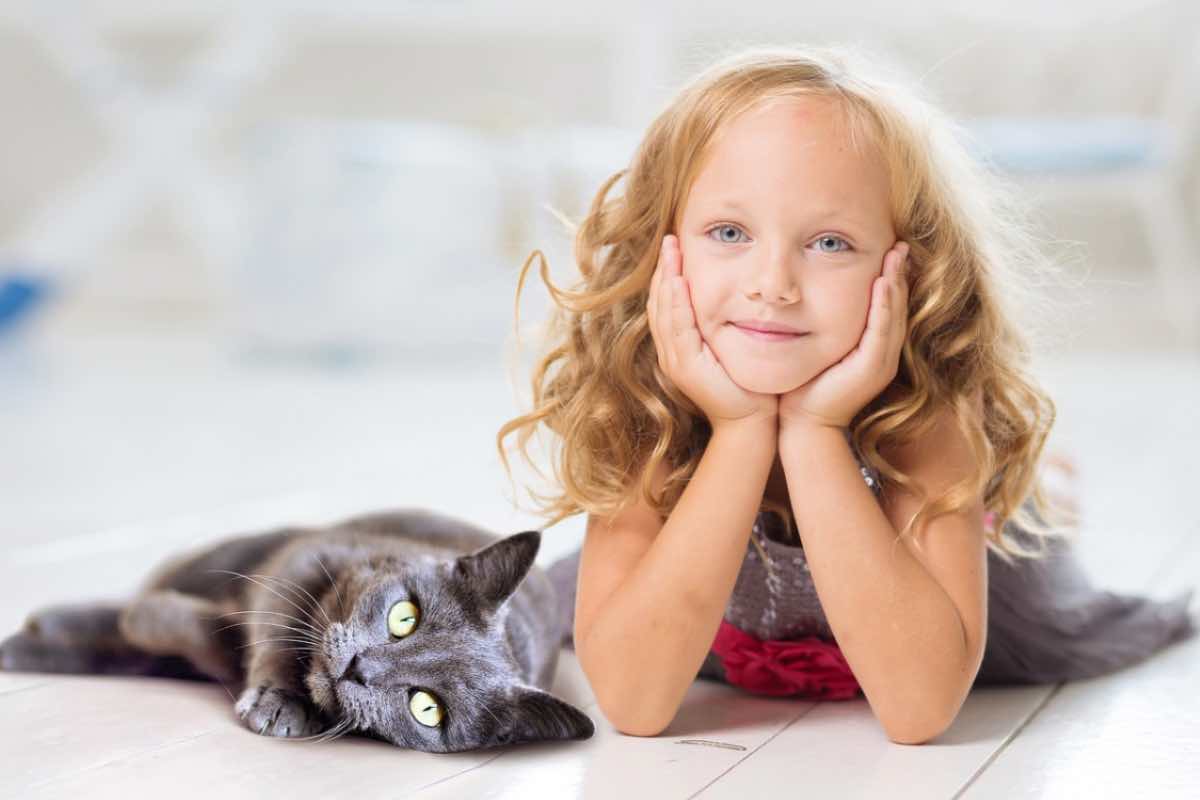 Gatto sdraiato accanto a una bambina felice