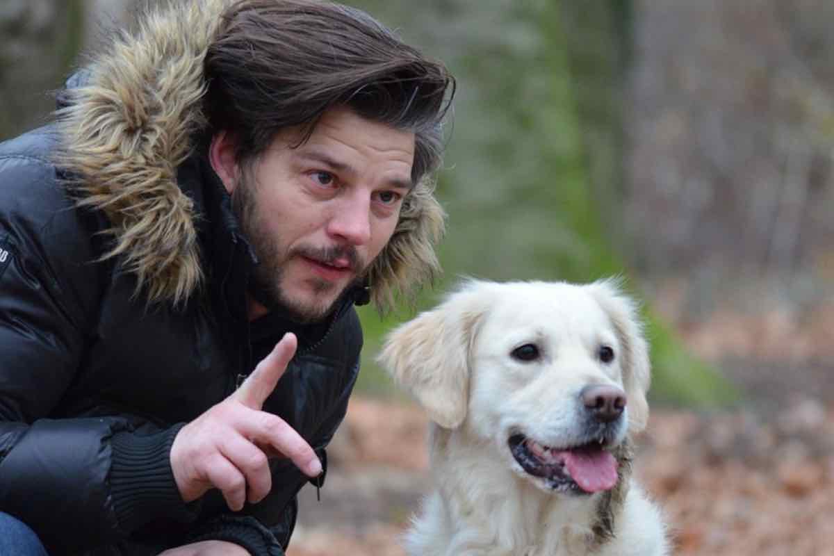 Uomo parla al suo cane bianco nel bosco