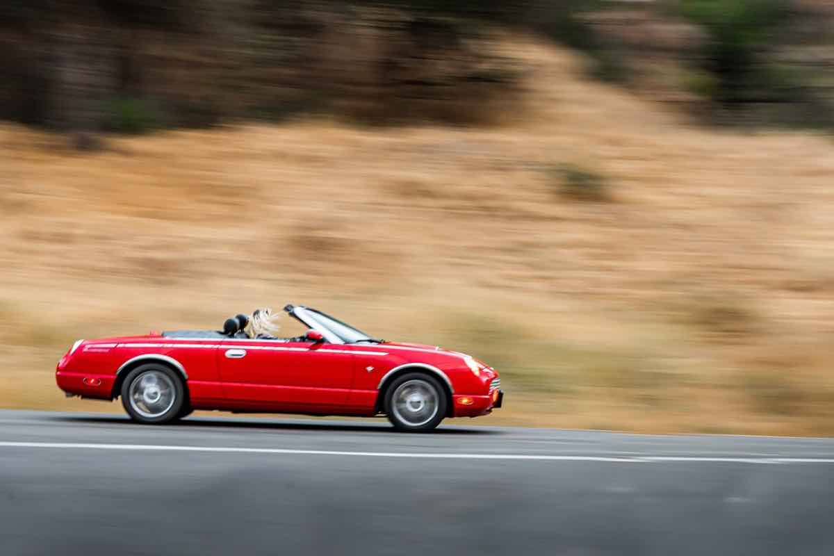 Auto rossa sfreccia in strada extraurbana